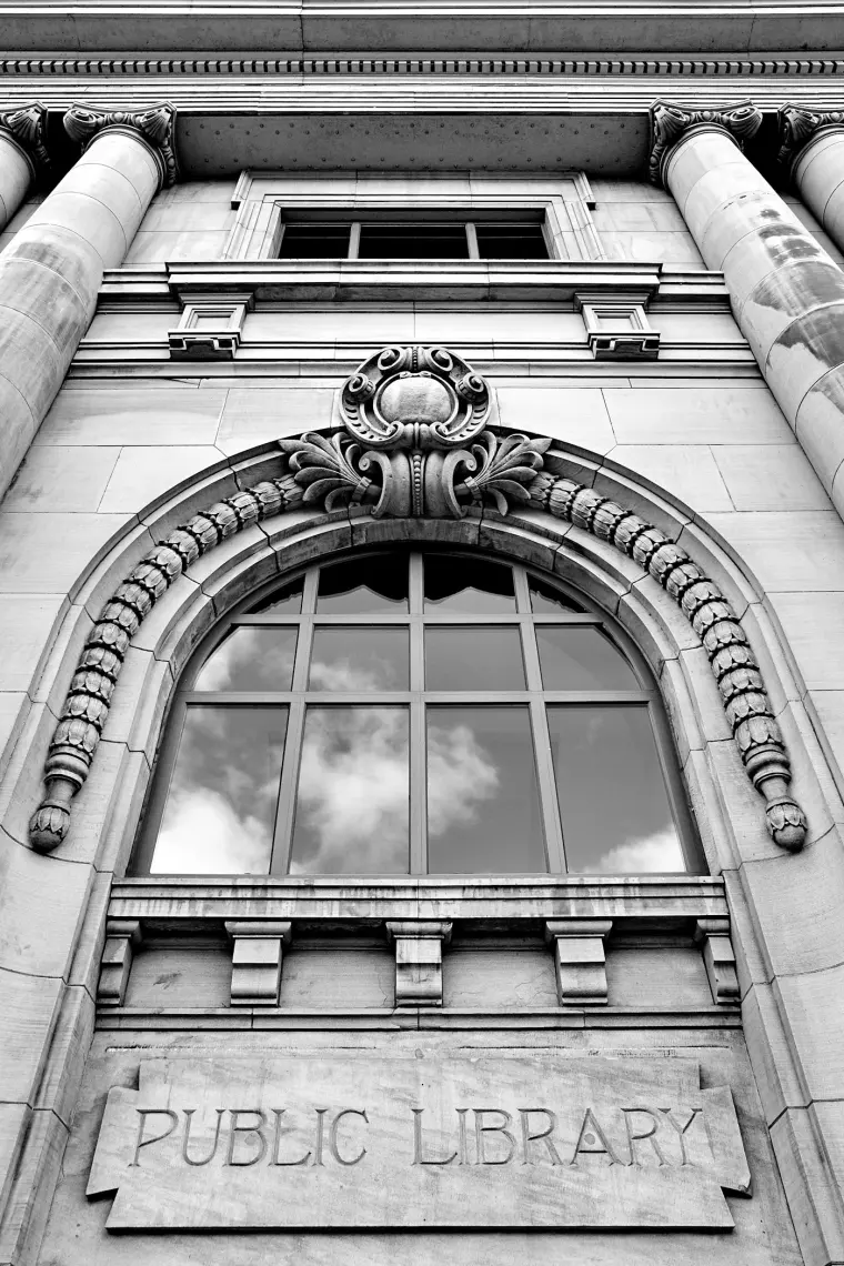 The carved stone facade of a public library, with PUBLIC LIBRARY cut into the lintel